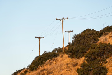 Old rural power lines above dry brush hillside near Los Angeles and Ventura County in Southern California.  