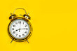 Reloj dorado con agujas despertador vintage sobre un fondo amarillo brillante liso y aislado. Vista superior y de cerca. Copy space