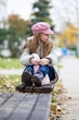Cute little girl imaginary sitting on bench at park in autumn chilly day 
