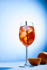 Wall Mural - cocktail Aperol Spritz with straw in glass and oranges on blue background