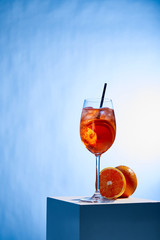 Wall Mural - cocktail Aperol Spritz with straw in glass and oranges on blue background