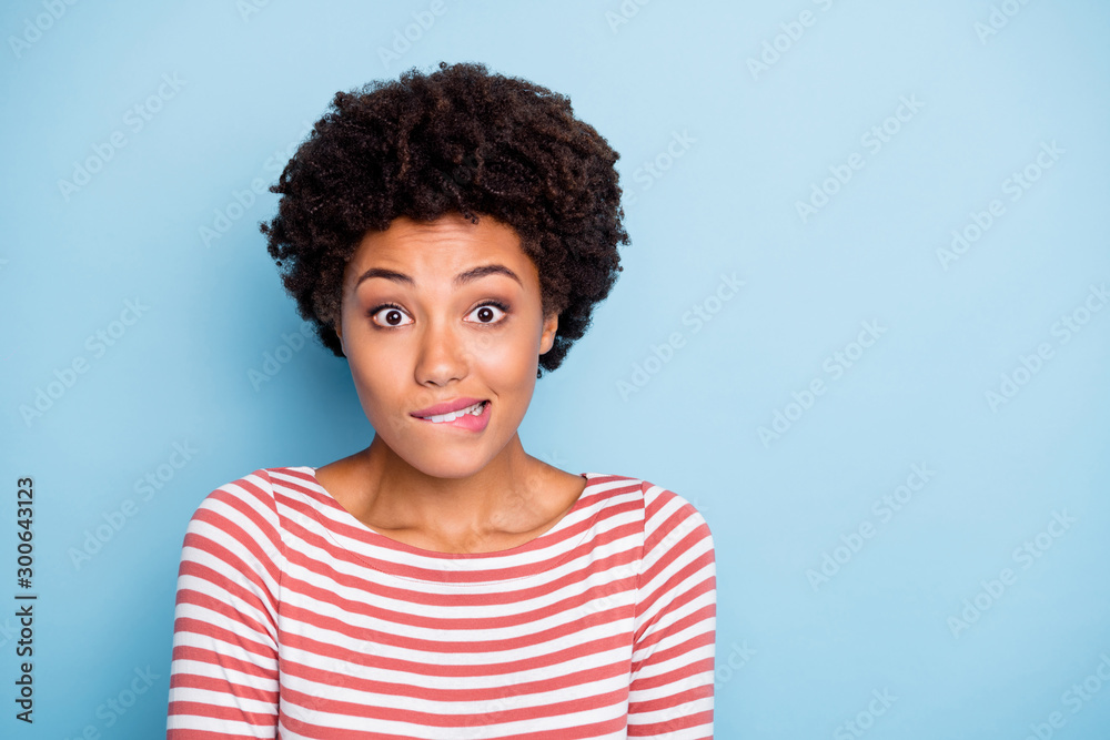 Oops. Closeup photo of pretty dark skin lady biting lips speechless made great mistake feel guilty wear striped shirt isolated blue color background - obrazy, fototapety, plakaty 