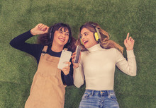 Pretty Teenagers Girl Friends In Headphones Listening To Music On Their Smart Phones