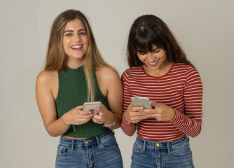 Two young beautiful girl friends on smart phone texting and chatting having fun on social media