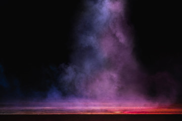 empty wooden table with colorful smoke float up on dark background