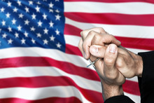 United States Flag And Praying Patriot Man With Crossed Hands. Holding Cross, Hoping And Wishing.