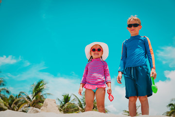 Wall Mural - cute kids - boy and girl- play with toys on beach