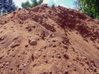 A mountain of sand and stones. Material for building a house in the village. Sand and gravel mixture for leveling a construction site, making the foundation of a building or a drainage layer. 