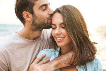 Wall Mural - image of young happy man kissing and hugging beautiful woman