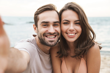 Wall Mural - photo of joyful young couple smiling and taking selfie photo