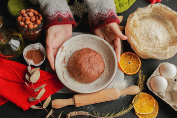 The process of making christmas cookies. Girl hands make the dough. Ingredients for baking a pie: flour, confectionery, dishes, kitchen utensils, spruce cookies figure on a dark background.Christmas g