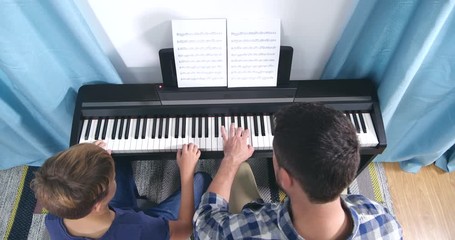 Poster - Man teaching boy to play piano in room, above view