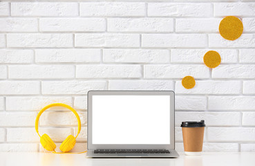 Modern laptop on desk near brick wall, space for design. Home workplace