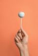 © New Africa - Woman holding sweet cake pop on coral background, closeup
