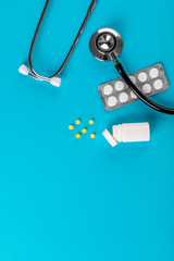 Wall Mural - pharmaceutical medicine pills, tablets and bottle end stethoscope isolated on blue background. Copy space for text