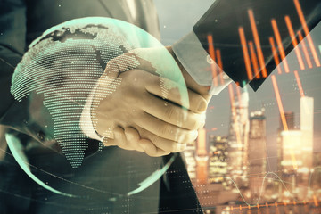 Double exposure of financial chart and world map on cityscape background with two businessmen handshake. Concept of international investment