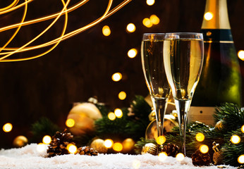 Two champagne glasses and christmas decoration on wooden snow golden bokeh background. Happy New Year Celebration. Selective focus and small depth of field