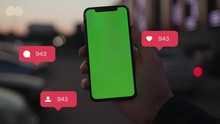 Hands Holding Use Smartphone With Vertical Green Screen On Night City Light Background Car Communication. Animation With User Interface - Likes, Followers, Comments For Social Media