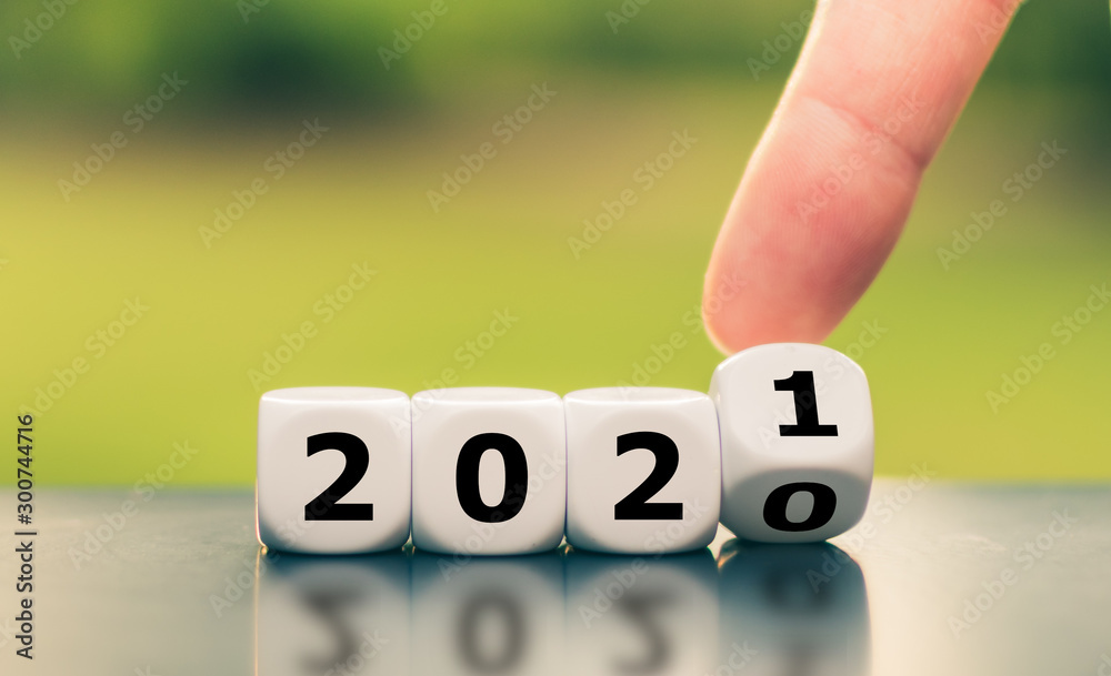 Hand turns a dice and changes the year "2020" to "2021". - obrazy, fototapety, plakaty 