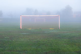 Fototapeta Sport - isolated soccer goal on a lonely soccer field early one misty foggy morning