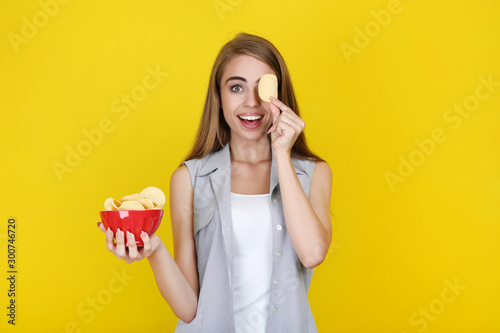 Fotomural Young beautiful girl with potato chips in bowl on yellow background