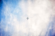 Low Angle Shot Of An Airplane Flying High In The Sky With Pure White Clouds