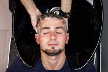 men wash their hair in a barbershop, a guy makes a haircut in a beauty salon, comfort concept