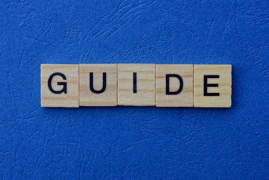 word guide made of brown wooden letters lies on a blue table