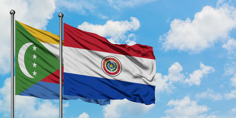 Comoros and Paraguay flag waving in the wind against white cloudy blue sky together. Diplomacy concept, international relations.