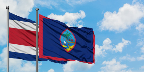 Costa Rica and Guam flag waving in the wind against white cloudy blue sky together. Diplomacy concept, international relations.