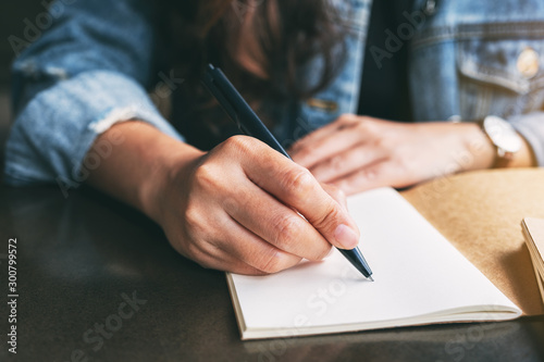 Cuadros en Lienzo Closeup image of a woman writing on a blank notebook on the table
