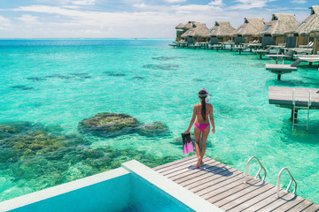 Luxury overwater bungalows Tahiti resort woman going snorkeling from private hotel room on Bora Bora island, French Polynesia. Travel vacation recreational activity watersport fun leisure.