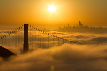 Spectacular Golden Gate Bridge sunrise with low fog and city view