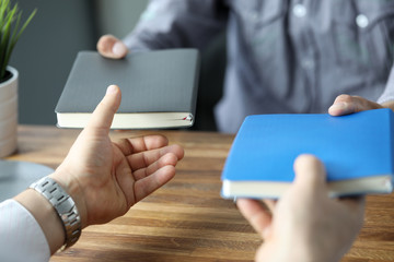 Two businessmen exchanging with notebooks at office workplace