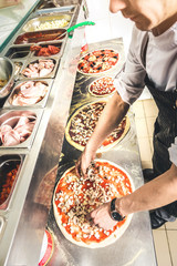 Wall Mural - Professional chef cooking in the kitchen restaurant at the hotel, preparing dinner. A cook in an apron makes a salad of vegetables and pizza.