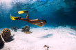 © artifirsov - Girl freediver glides with yellow fins over sandy sea.