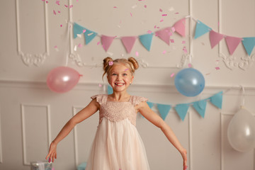 Wall Mural - Happy birthday Portrait of a happy cute blonde 7-8 years old in a festive decor with confetti and gifts.