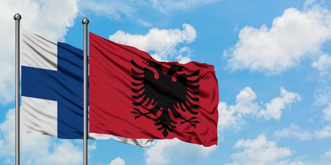 Finland and Albania flag waving in the wind against white cloudy blue sky together. Diplomacy concept, international relations.