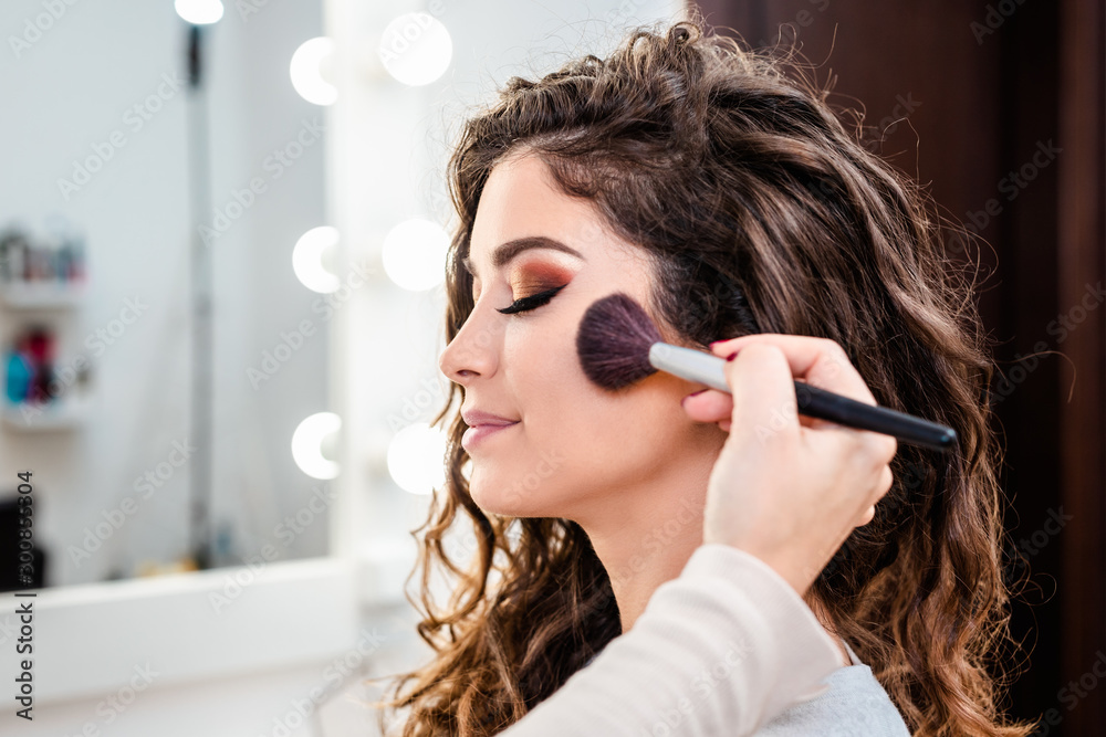 Make up artist applying professional make up of beautiful young woman. - obrazy, fototapety, plakaty 