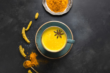 Wall Mural - Golden turmeric milk with curcuma powder and anise star on black. View from above.