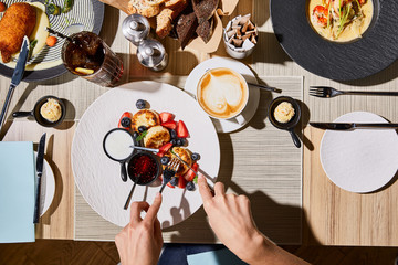 Wall Mural - top view of woman eating delicious syrniki at restaurant