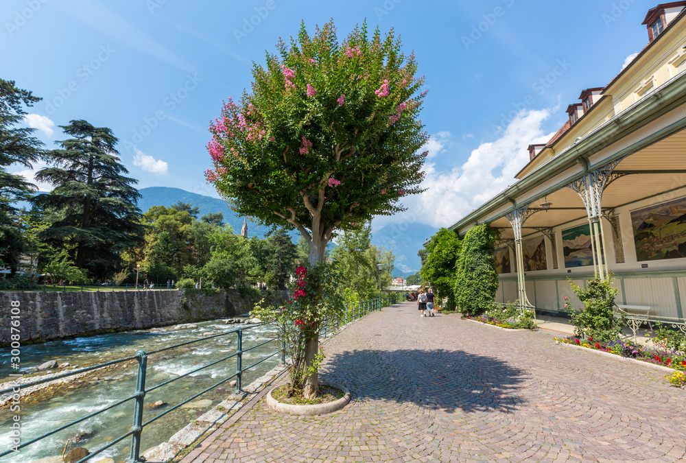 MERANO, ITALY - JULY 20, 2019 - Merano Winterpromenade along the torrente Passirio. Its most distinctive landmark is the Wandelhalle covered passageway - obrazy, fototapety, plakaty 