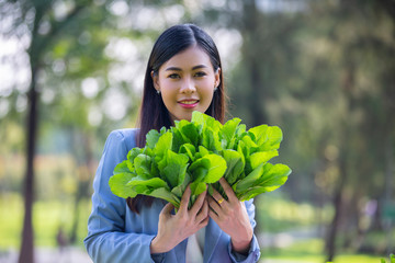 Asian women smiling and hand holding organic vegetable at farm plantation