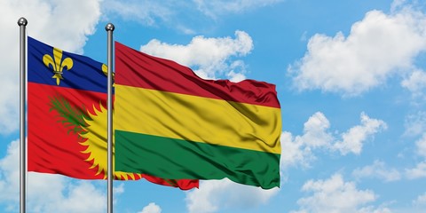 Guadeloupe and Bolivia flag waving in the wind against white cloudy blue sky together. Diplomacy concept, international relations.