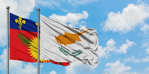 Guadeloupe and Cyprus flag waving in the wind against white cloudy blue sky together. Diplomacy concept, international relations.