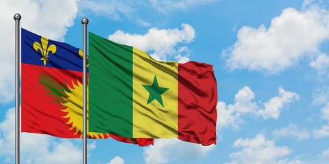 Guadeloupe and Senegal flag waving in the wind against white cloudy blue sky together. Diplomacy concept, international relations.