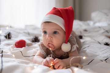 little cute baby girl portreit in red christmas santa hat with lights