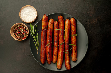 Wall Mural - Grilled sausages on a plate with spices and rosemary on a stone table