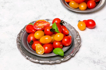 Wall Mural - Colorful organic cherry tomatoes on silver plates, light background.