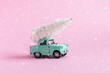 toy car with Christmas tree on it on pink background with snow texture , Christmas pr